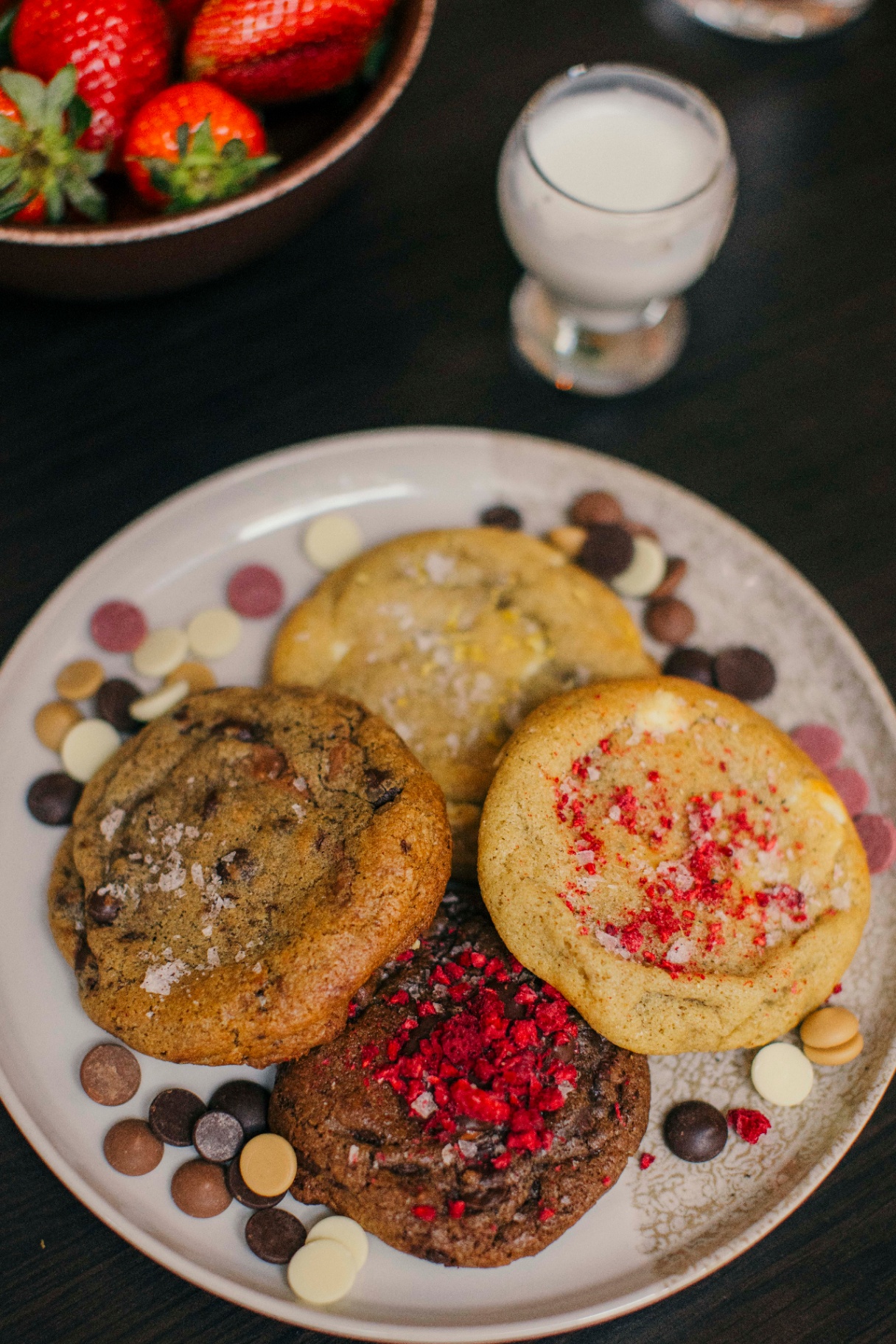 Fyra olika cookies på ett fat med chokladknappar runtom